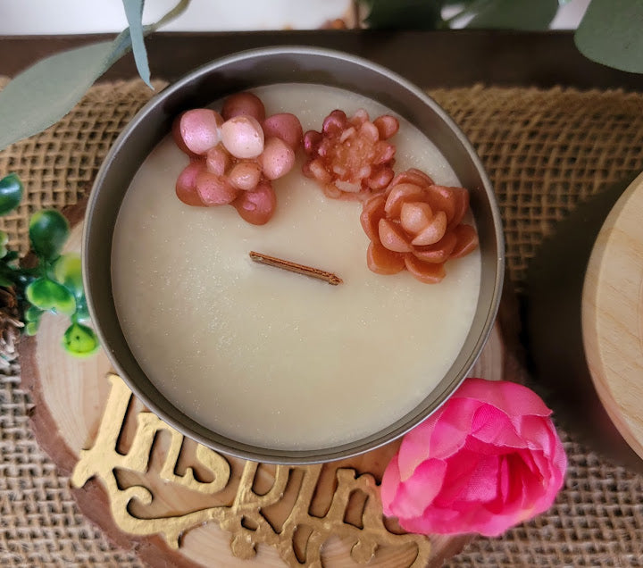 sugar woods-Uplifting Spiritual Kandle

5oz ~ 141.7 Champagne Gold Metal Tin, Faux woodgrain lid - 100% Soy Wax

This beautiful kandle is a classic white kandle with shimmering rosey succulents and a crackling wood wick.

This fragrance is infused with sparkling bubbles, citrus, wildflowers, poppies, violets, peony, white musk, amber, sandalwood and vanilla bean. This fragrance is a light and fun. It will elevate your mood.

Succulents represent enduring, timeless love, and adaptability, reminding us to ove